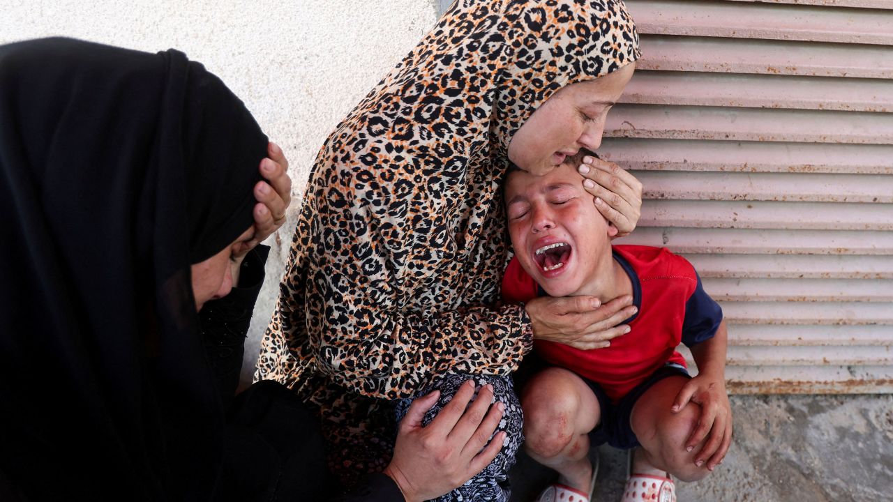 A Palestinian woman comforts a child as casualties are brought into Al-Aqsa Martyrs Hospital following an Israeli strike, in Deir al-Balah, central Gaza Strip, July 10, 2025.