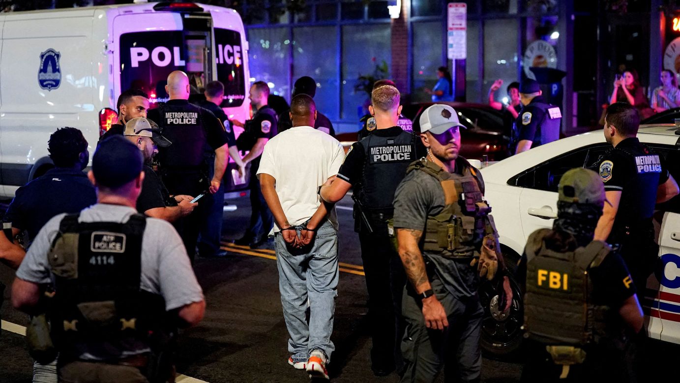 A detained man is led to a Metropolitan Police Department transport vehicle during a traffic stop in Washington, DC, on August 17, 2025.