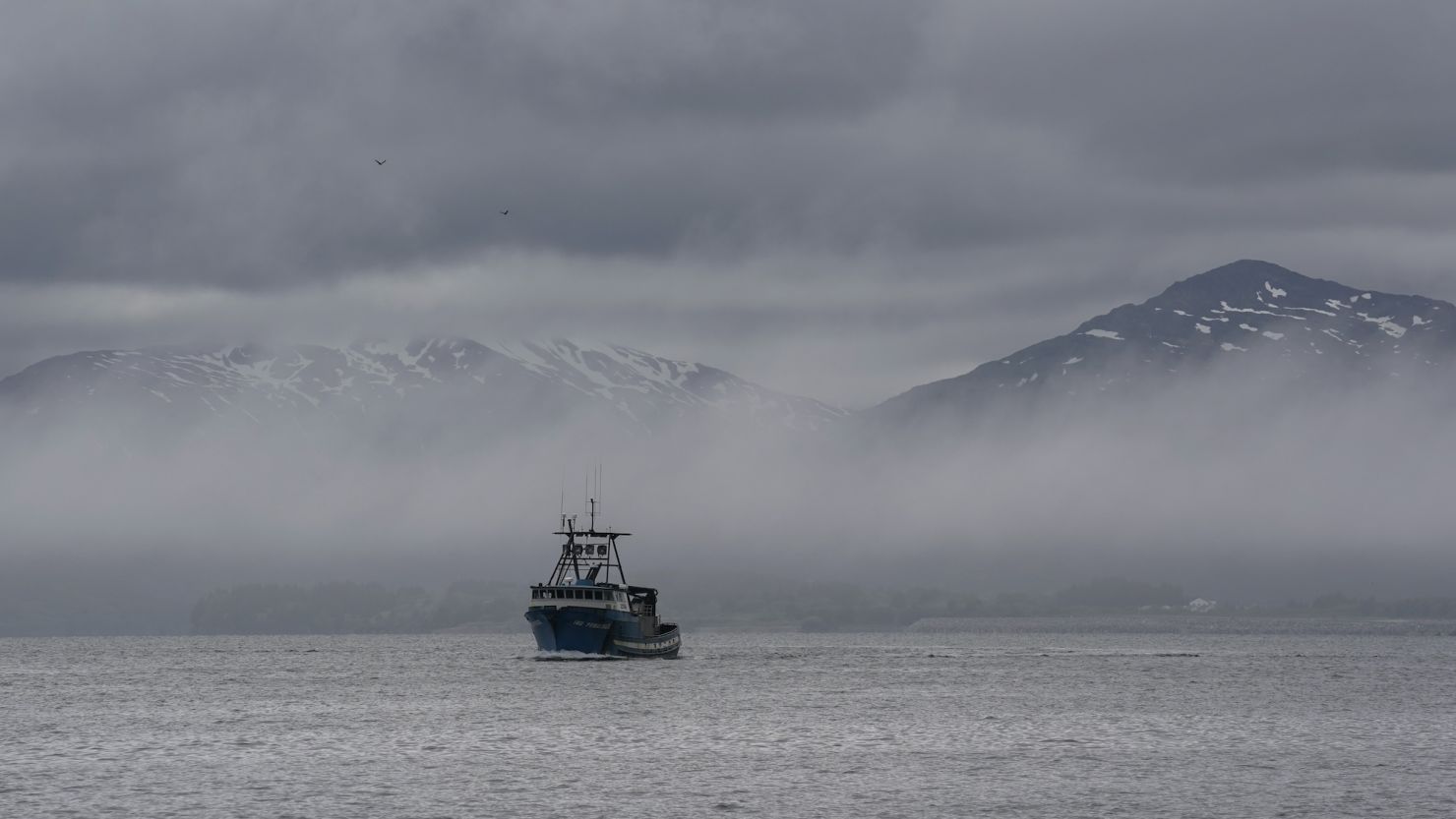 A boat in front of the snow-covered mountains in Kodiak, Alaska, in June 2023.