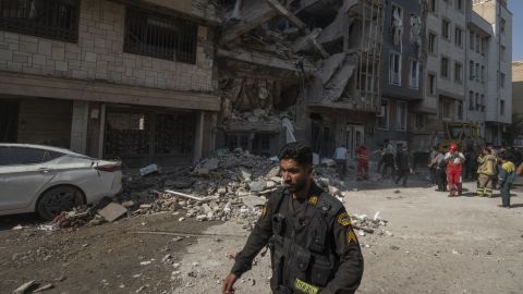 A police officer walks past a destroyed residential building after Israeli strikes in the Iranian capital of Tehran on Friday, June 13.