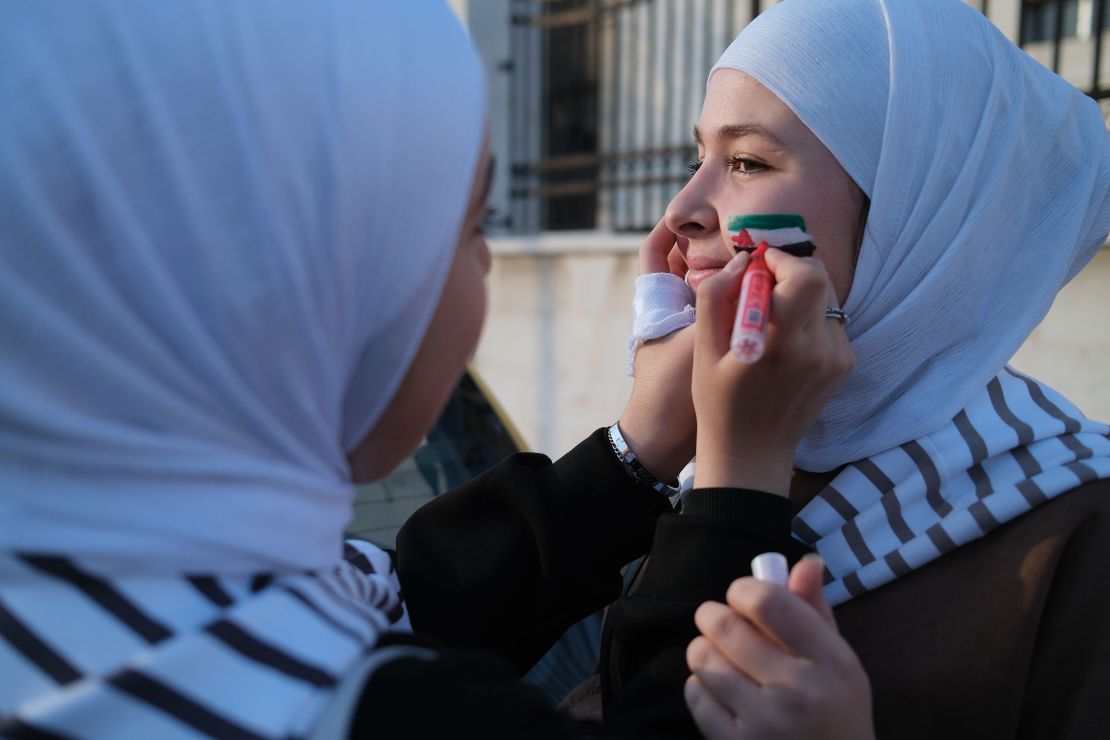 Young girls paint the Syrian opposition flag on each other’s faces.