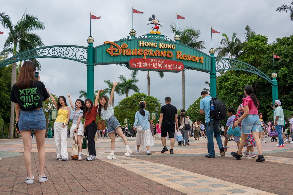 People pose for pictures at the entrance of Hong Kong Disneyland.