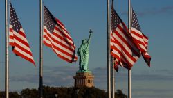 JERSEY CITY, NJ - OCTOBER 8: The sun sets on the Statue of Liberty in New York City and American flags in Liberty State Park on October 8, 2022, in Jersey City, New Jersey.  (Photo by Gary Hershorn/Getty Images)