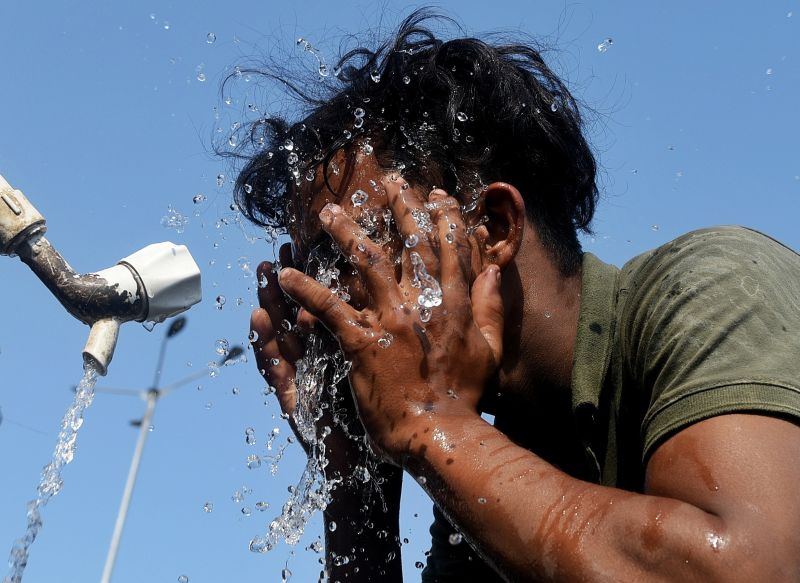 A worker is applying water to his face during the ongoing heatwave in Mumbai, India, on April 22, 2024. (Photo by Indranil Aditya/NurPhoto via Getty Images)