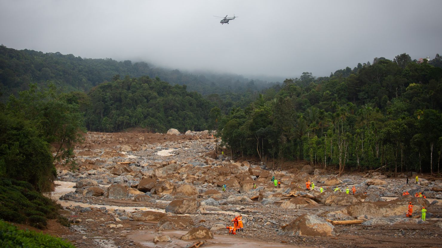 Rescuers look for survivors as an Indian Air Force helicopter flies overhead at the site of the landslide on July 31, 2024 in Mundakkai village, India.