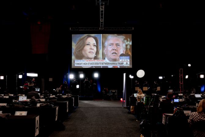 Images of Harris and Trump are seen on a screen inside the spin room before the debate.