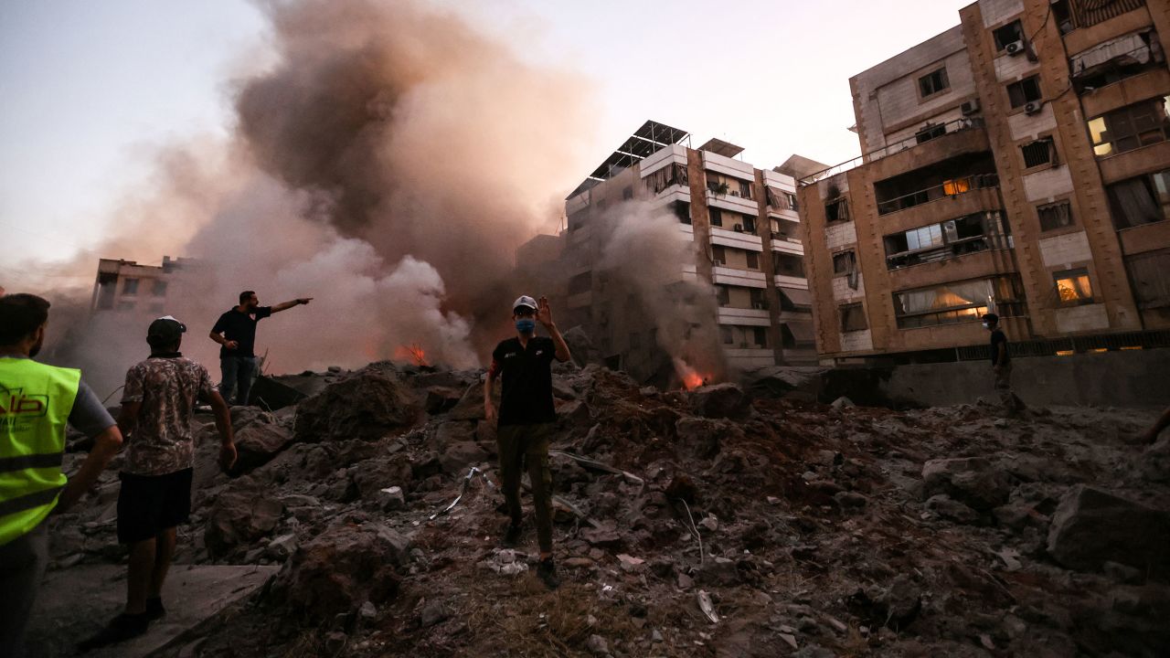 Rescue workers stand on the rubble of a building destroyed in an Israeli air strike on Friday.