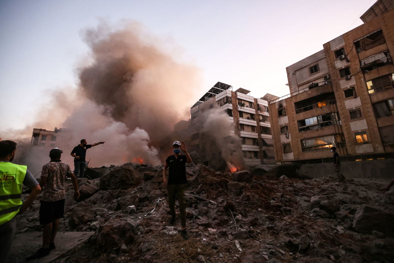 Rescue workers stand on the rubble of a building destroyed in an Israeli air strike on Friday.