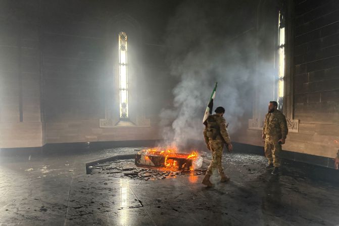 Rebel fighters stand next to the burning gravesite of Syria's late president Hafez al-Assad at his mausoleum in the family's ancestral village of Qardaha, in the western Latakia province, on December 11. The father and predecessor of Syria's ousted president Bashar al-Assad died in 2000.