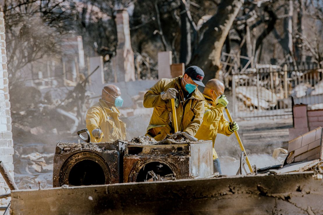 Pasadena firefighters clean the debris of a burned home destroyed in the Eaton Fire.