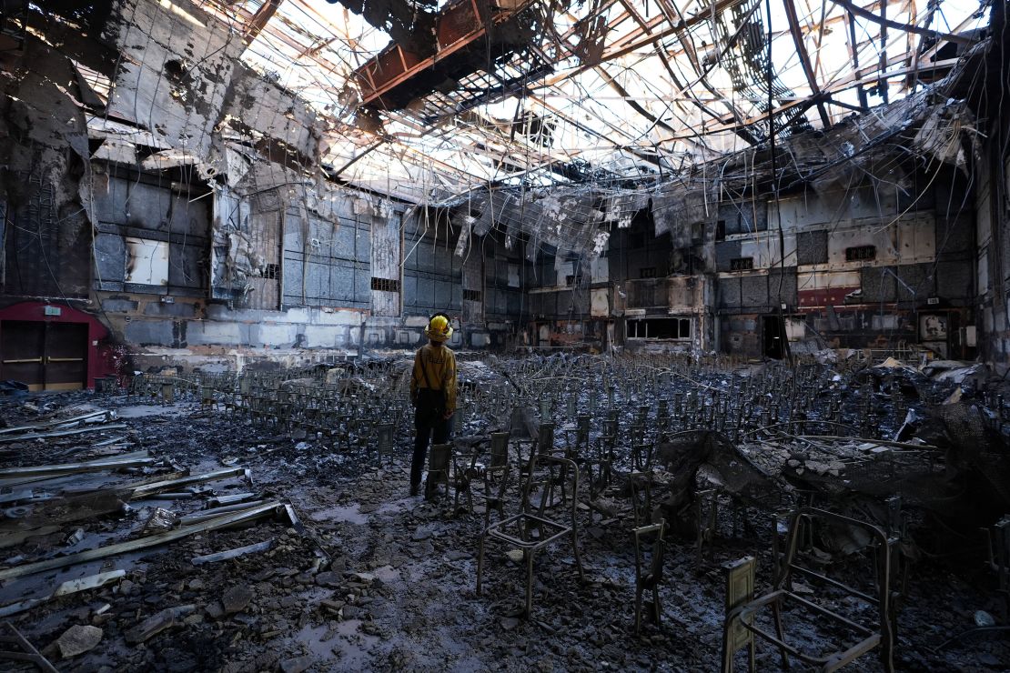 A firefighter stands in the burnt down auditorium of the Eliot Arts Magnet Academy in Altadena on Sunday.