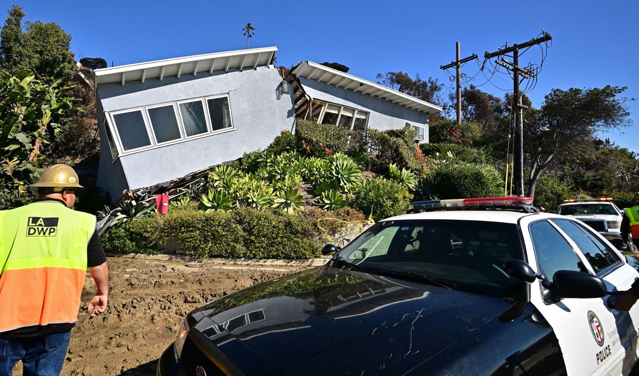 Los Angeles Department of Water and Power employees stand Thursday outside a house unscathed by the Palisades Fire, then split in half by a landslide in the Pacific Palisades neighborhood of Los Angeles.