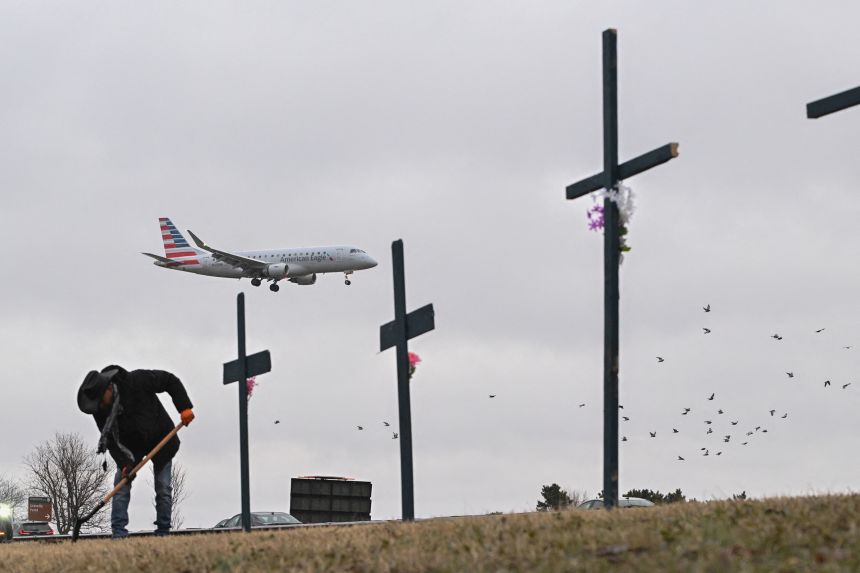 Roberto Marquez from Dallas, Texas, sets up a makeshift memorial on January 31 for the victims of the deadly midair collision near Reagan National Airport in Arlington, Virginia.