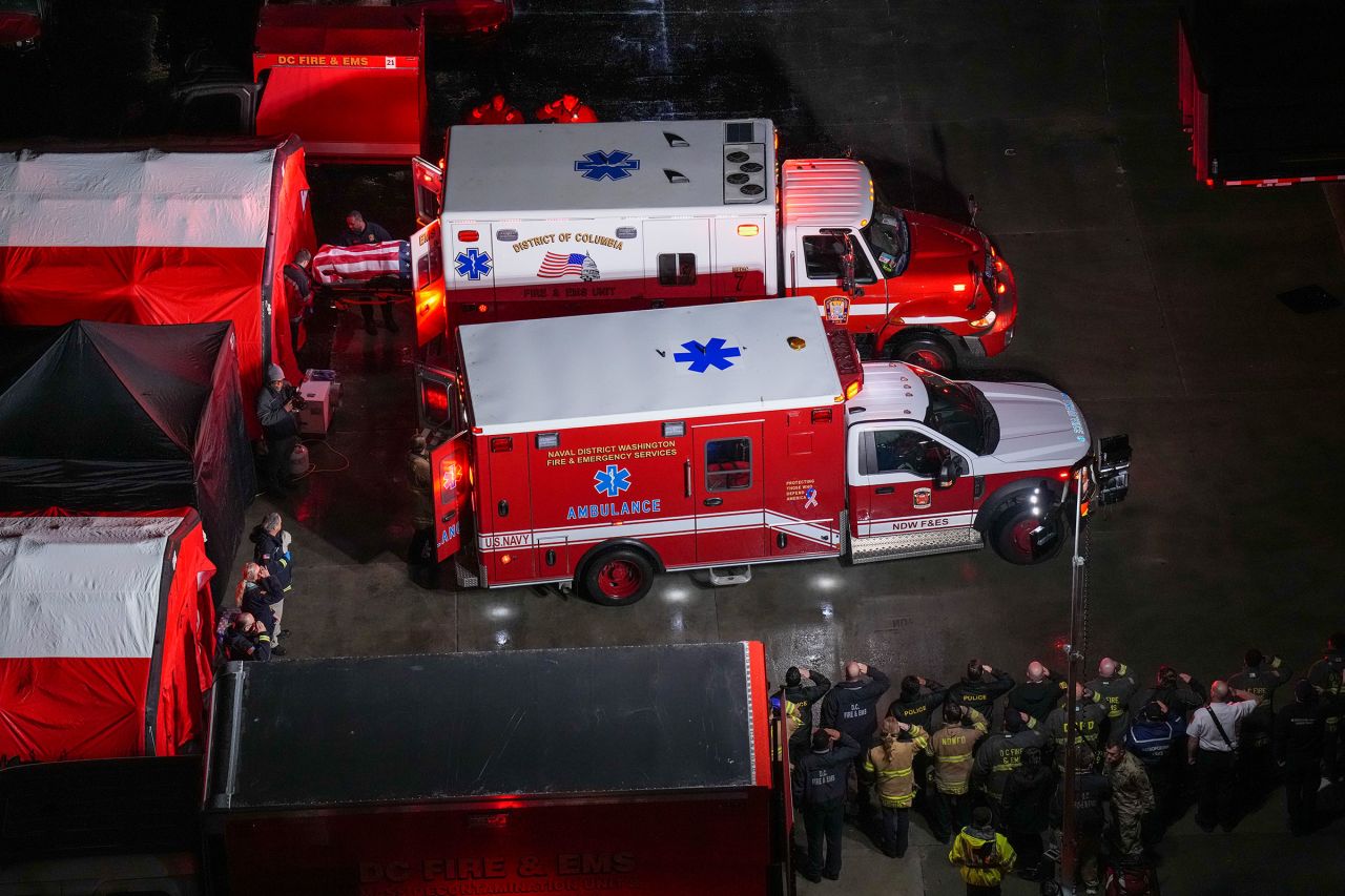 Local first responders salute the flag-draped bodies of the service members.