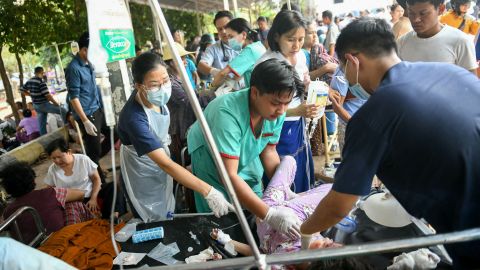 Medical workers treat an earthquake survivor on a bed in Myanmar.