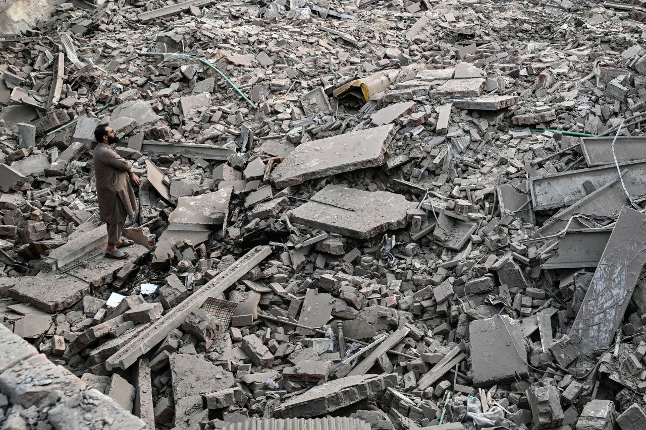 A man stands on the debris of a destroyed building at the Government Health and Educational complex in Muridke, Pakistan, on Wednesday.