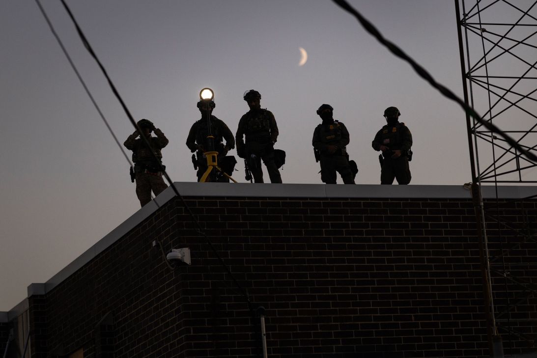 Federal law enforcement agents watch demonstrators outside of an immigrant processing center on September 27 in Broadview, Illinois.
