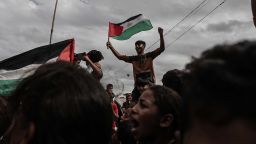 DEIR AL BALAH, GAZA - OCTOBER 09: Palestinians, including children, gathered at the Nuseirat refugee camp celebrate with Palestinian flags after the announcement of the ceasefire agreement in Gaza on October 09, 2025 in Deir al-Balah, Gaza. A ceasefire agreement between Israel and Hamas came into effect in the Gaza Strip on Thursday following marathon mediation efforts to end a two-year deadly war in the Palestinian enclave. Israel's public broadcaster KAN confirmed that the ceasefire deal took effect in the enclave. (Photo by Moiz Salhi/Anadolu via Getty Images)