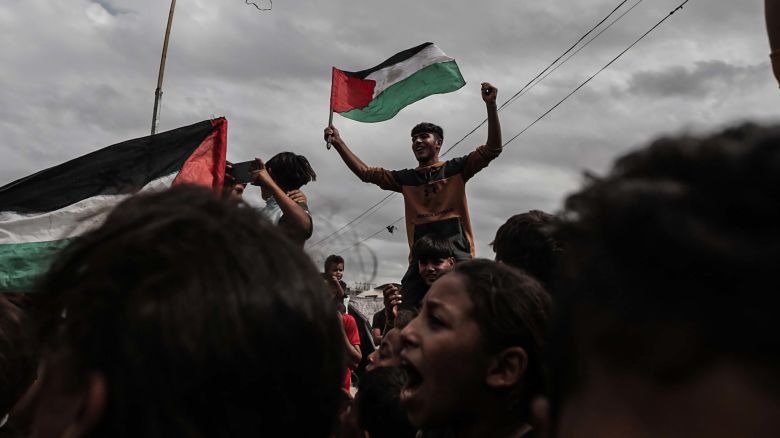 DEIR AL BALAH, GAZA - OCTOBER 09: Palestinians, including children, gathered at the Nuseirat refugee camp celebrate with Palestinian flags after the announcement of the ceasefire agreement in Gaza on October 09, 2025 in Deir al-Balah, Gaza. A ceasefire agreement between Israel and Hamas came into effect in the Gaza Strip on Thursday following marathon mediation efforts to end a two-year deadly war in the Palestinian enclave. Israel's public broadcaster KAN confirmed that the ceasefire deal took effect in the enclave. (Photo by Moiz Salhi/Anadolu via Getty Images)
