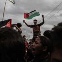 DEIR AL BALAH, GAZA - OCTOBER 09: Palestinians, including children, gathered at the Nuseirat refugee camp celebrate with Palestinian flags after the announcement of the ceasefire agreement in Gaza on October 09, 2025 in Deir al-Balah, Gaza. A ceasefire agreement between Israel and Hamas came into effect in the Gaza Strip on Thursday following marathon mediation efforts to end a two-year deadly war in the Palestinian enclave. Israel's public broadcaster KAN confirmed that the ceasefire deal took effect in the enclave. (Photo by Moiz Salhi/Anadolu via Getty Images)