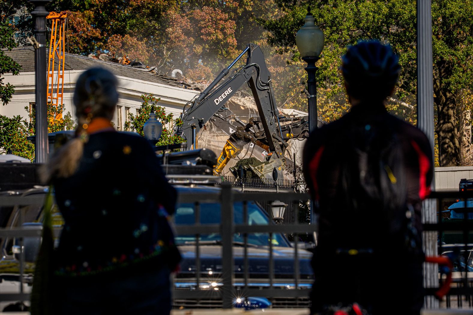 Pedestrians stop to watch the facade of the East Wing being demolished on October 21.