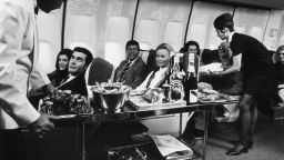 A steward and stewardess serving first-class passengers with drinks and refreshments on board a Boeing 747.   (Photo by Fox Photos/Getty Images)