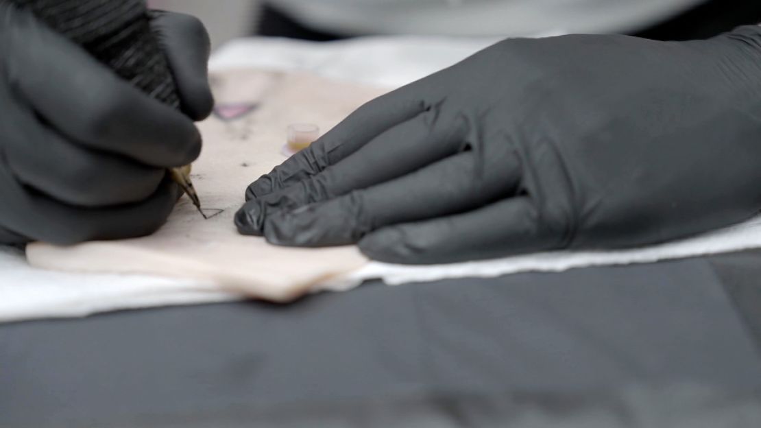 A tattoo artist in London practices with smart ink developed by researcher Ali Yetisen on a piece of pig skin.