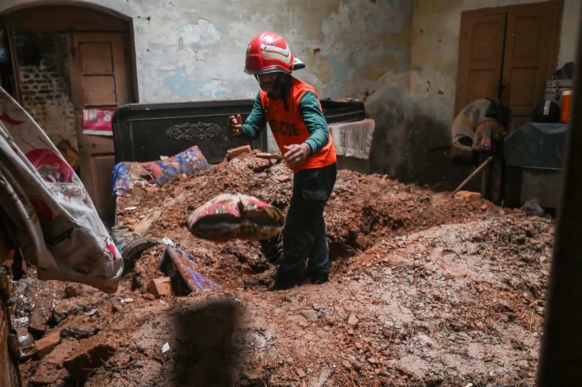 A rescue worker clears debris from a collapsed roof after heavy rains hit Lahore, Pakistan, on July 10.
