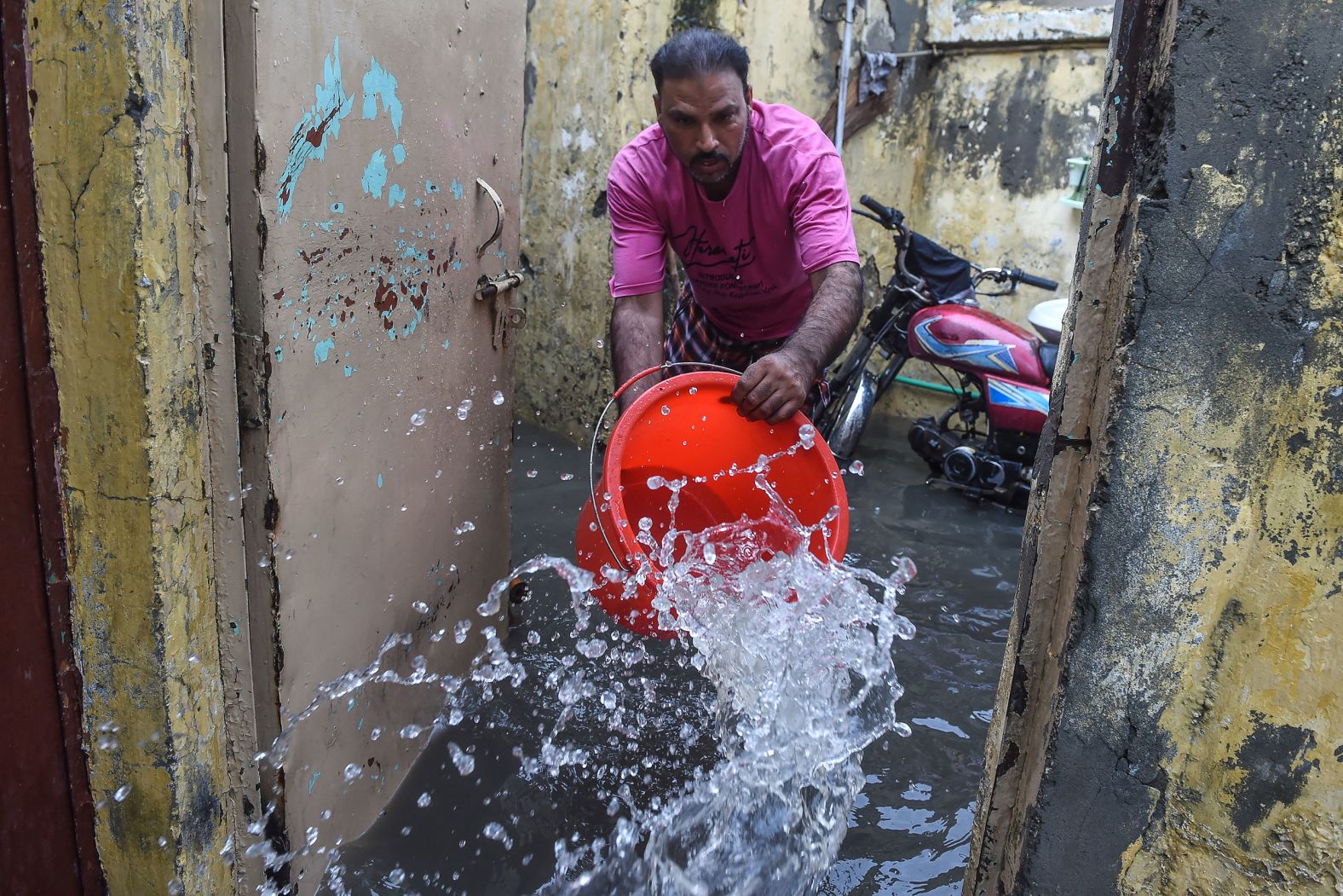 A resident uses a bucket to remove water from his home in Lahore, Pakistan, on July 10.