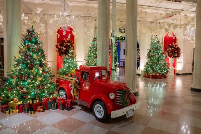 Christmas trees trimmed with red and green plaid décor, as well as a vintage red truck, complete the holiday scenery.