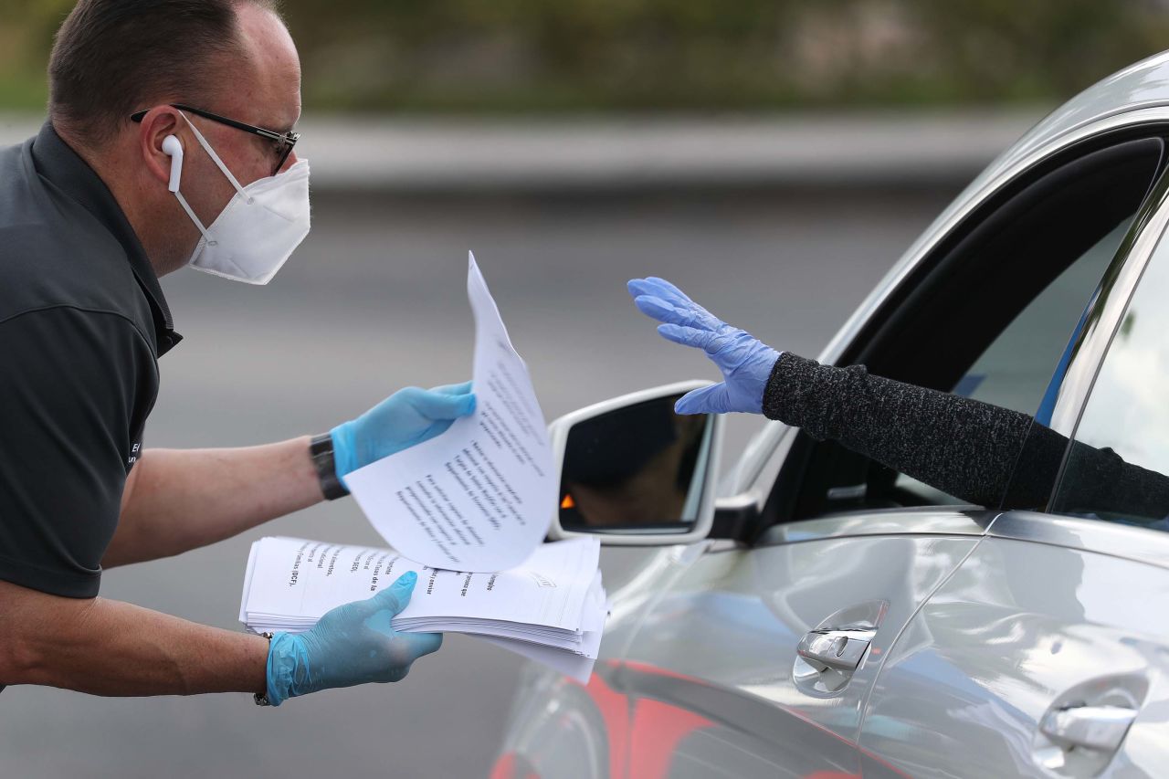 Eddie Rodriguez, who works for the City of Hialeah, Florida, hands out unemployment applications to people in their vehicles on April 8.