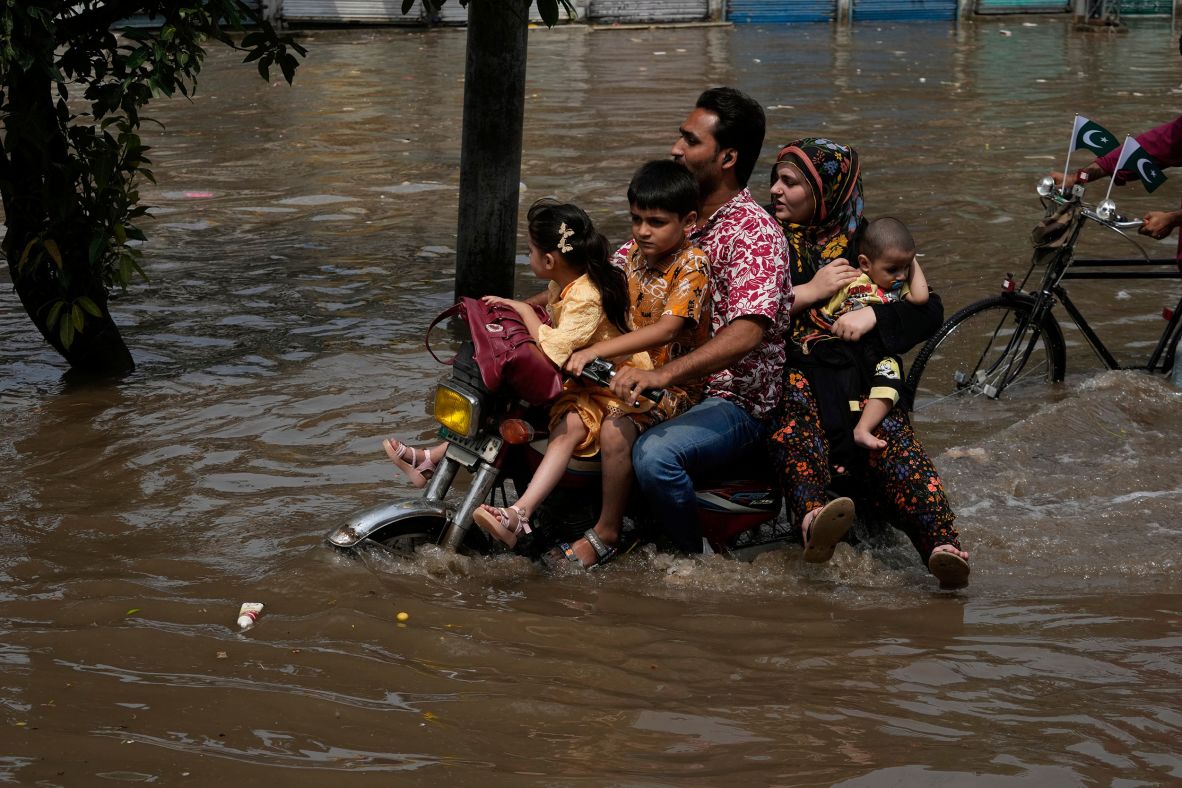 Motorists ride through a flooded road in Lahore, Pakistan, on August 3.