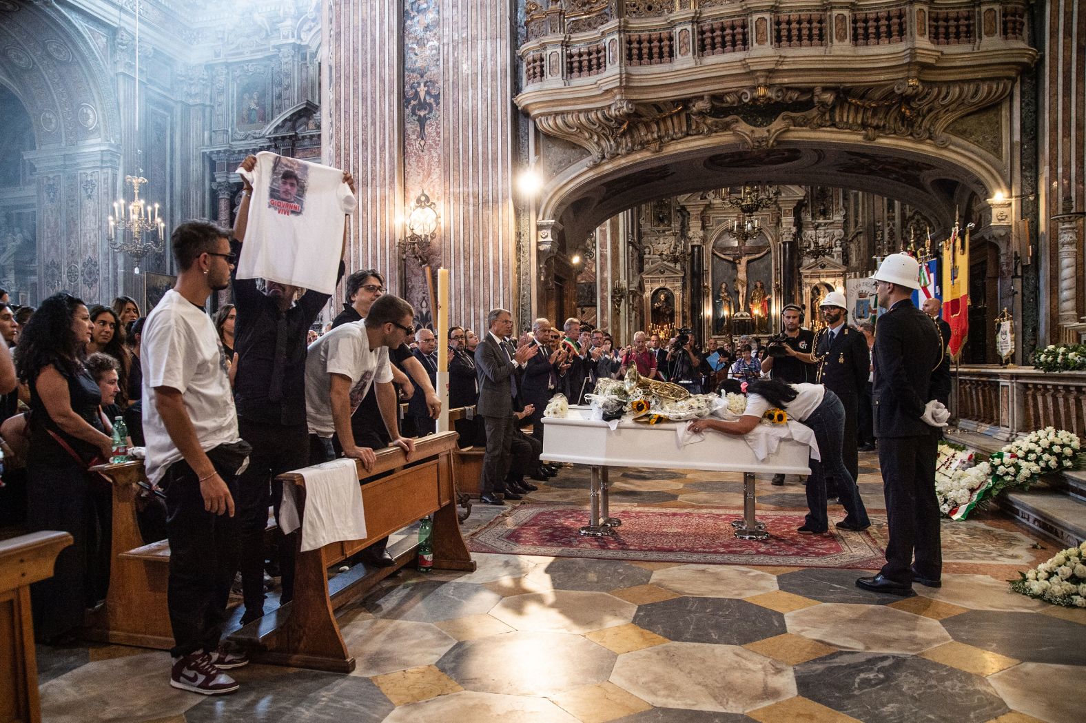 The mother of Giovanbattista "Giogiò" Cutolo lies on his coffin during his funeral in Naples, Italy, on Wednesday, September 6. Cutolo, 24, was fatally shot last month.