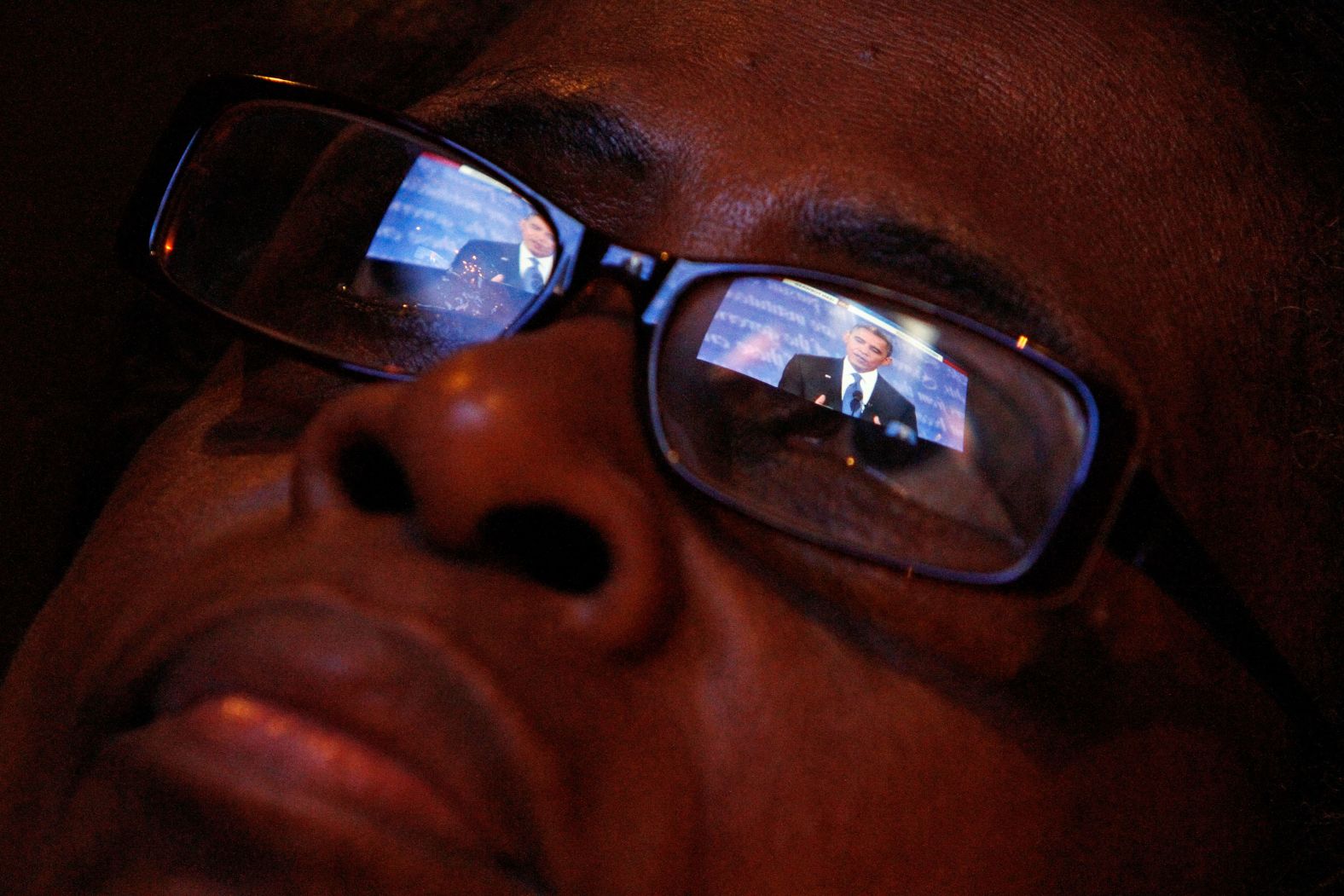 Obama is reflected in Mary Jackson's eyeglasses as she watches his first presidential debate with Mitt Romney in 2012.
