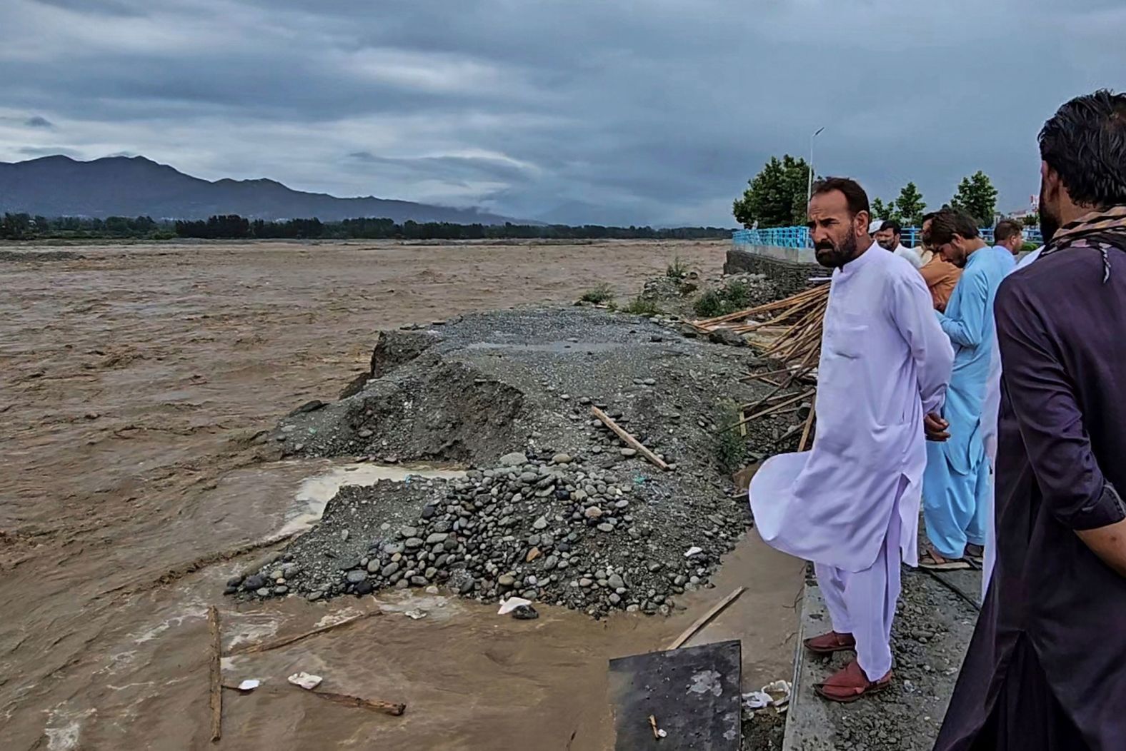 Local residents look at the overflowing Swat River on the outskirts of Mingora, Pakistan, on June 27.