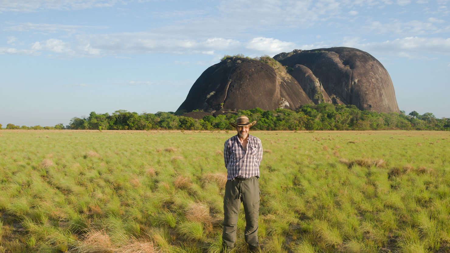 Dr José Oliver, a reader of Latin American archaeology at the University College London, shows the scale of the granite hills that bear monumental rock art.