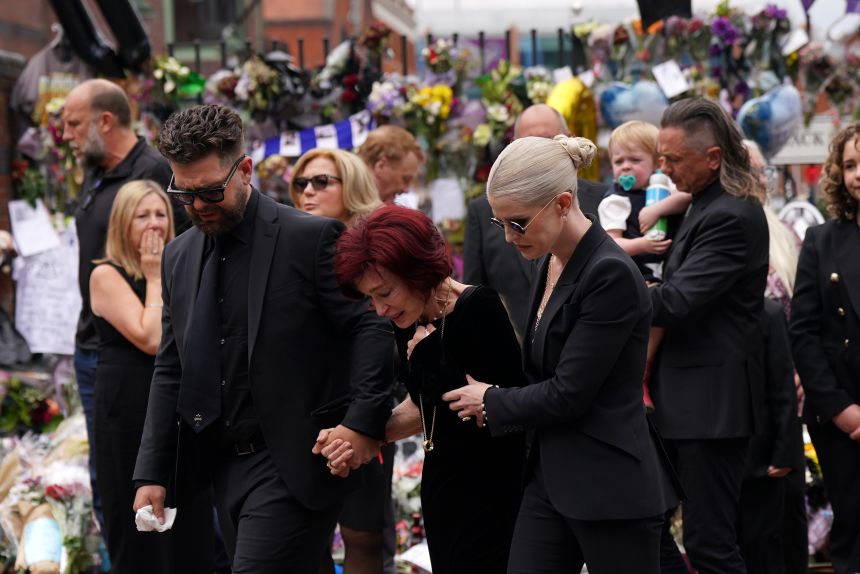 The family of Ozzy Osbourne (left to right) Jack, Sharon and Kelly Osbourne, view the messages and floral tributes left at the Black Sabbath Bridge bench on Broad Street in Birmingham in memory of Black Sabbath frontman Ozzy Osbourne, as his body is brought back to his home city for a procession on Wednesday July 30, 2025.