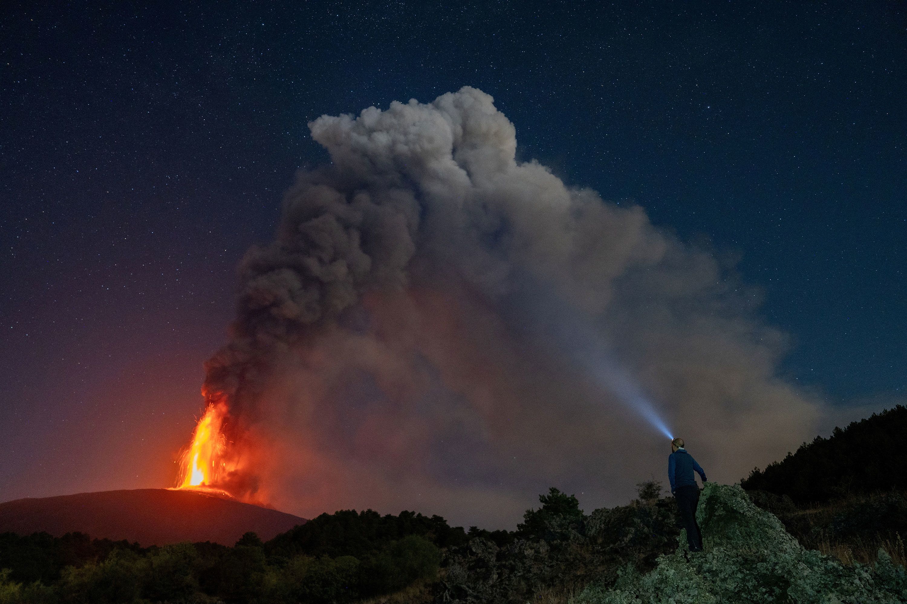 A person in Sicily, Italy, watches lava and smoke rise from a crater of Mount Etna, Europe's most active volcano, on Monday, July 15.