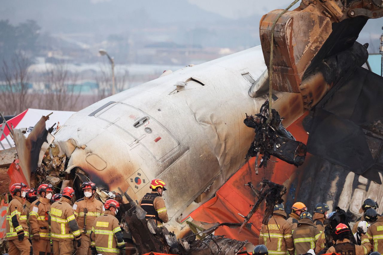 An excavator is used to lift burnt chairs from the wreckage.