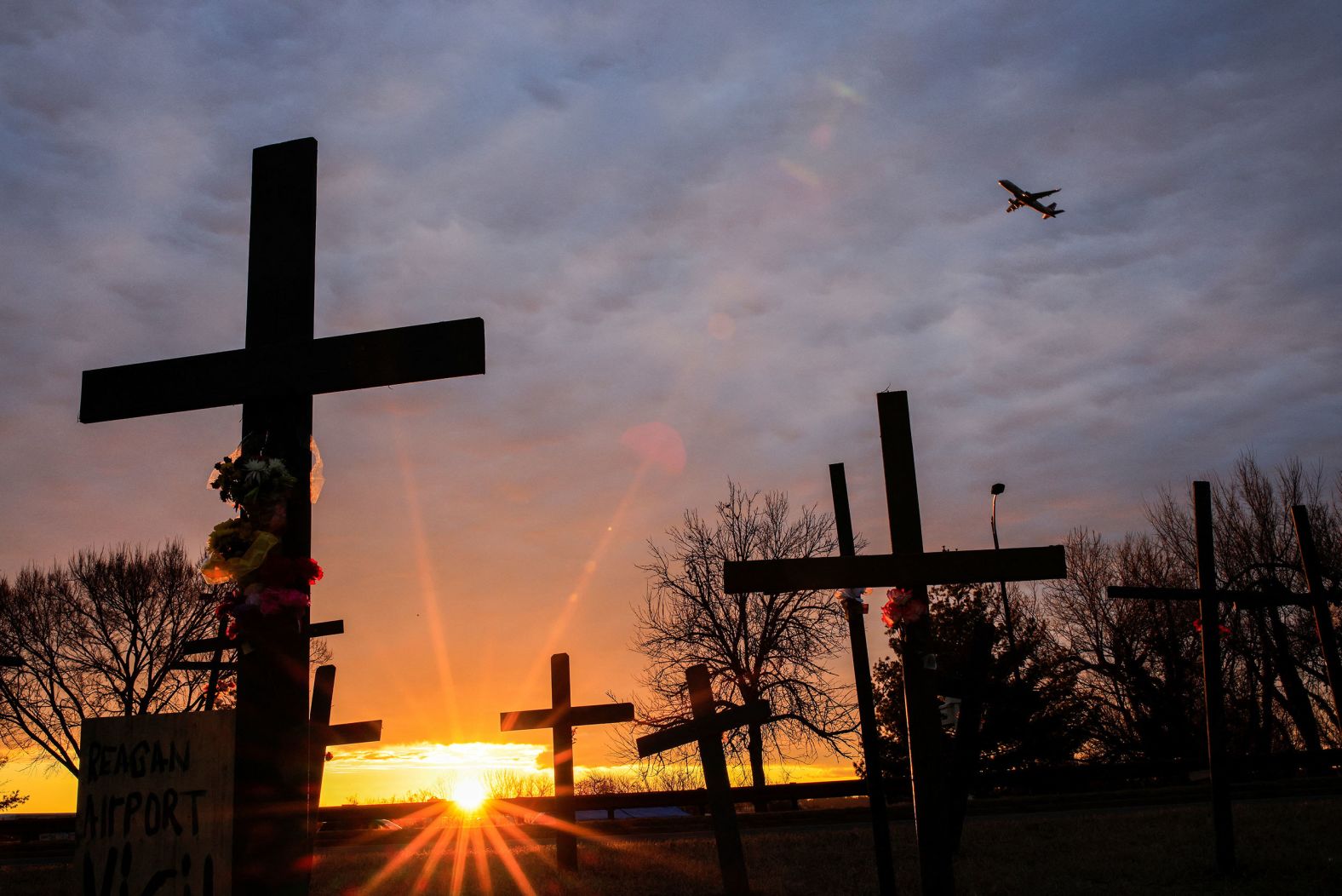 A plane flies over makeshift crosses that were put up for the victims near Reagan National Airport.