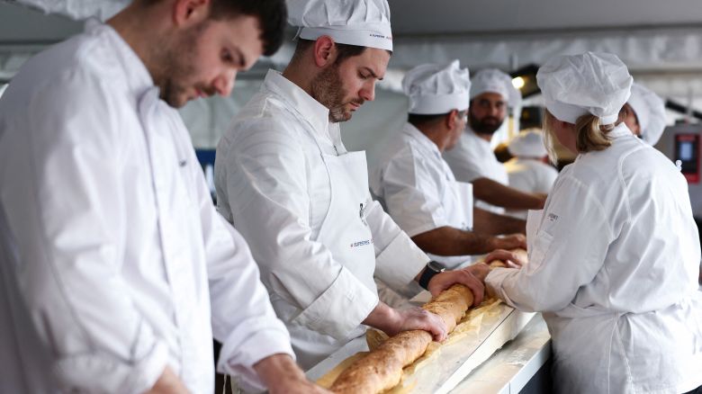French bakers try not to crack the baguette when it comes out of a large rotating oven in an attempt to beat the world record for the longest baguette during the Suresnes Baguette Show in Suresnes near Paris, France, May 5, 2024. REUTERS/Stephanie Lecocq