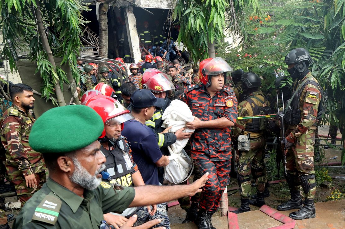 Emergency crews carry the body of a person who was killed after the crash in Dhaka, Bangladesh, on Monday.
