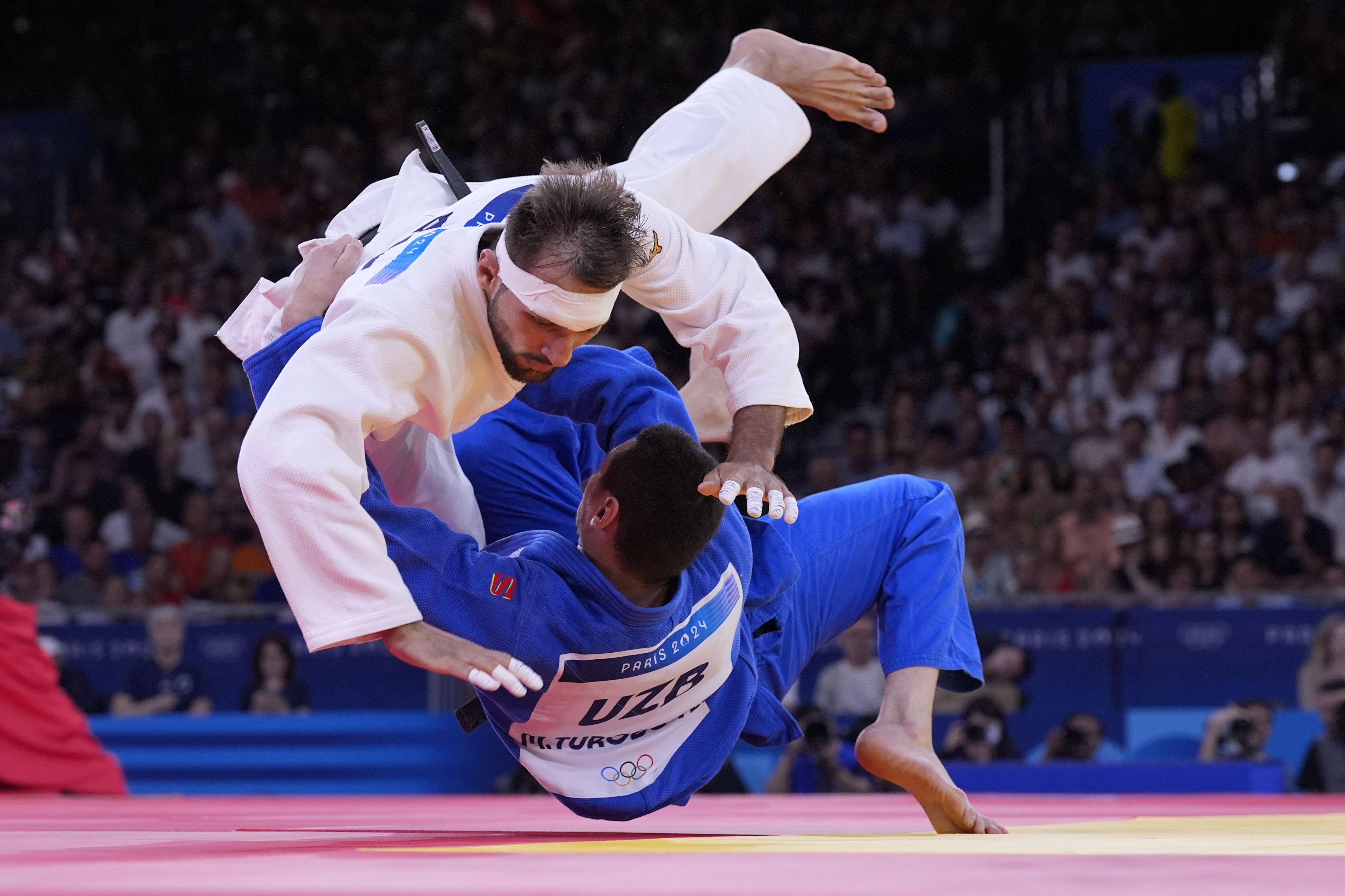 Azerbaijan's Zelym Kotsoiev, top, and Uzbekistan's Muzaffarbek Turoboyev compete in a judo semifinal on August 1. <a href="https://www.cnn.com/sport/live-news/paris-olympics-news-2024-08-01-24#h_64b2fa86bf716965285544ea96743ae2">Kotsoiev would go on to win the gold</a>. Toroboyev won the bronze.