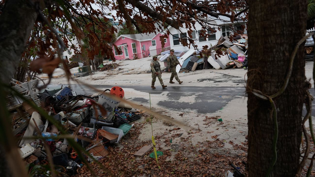 Members of the Florida Army National Guard check for any remaining residents in nearly deserted Bradenton Beach, where piles of debris from Hurricane Helene still sit outside damaged homes, ahead of the arrival of Hurricane Milton, Tuesday, October 8, 2024, on Anna Maria Island, Florida.