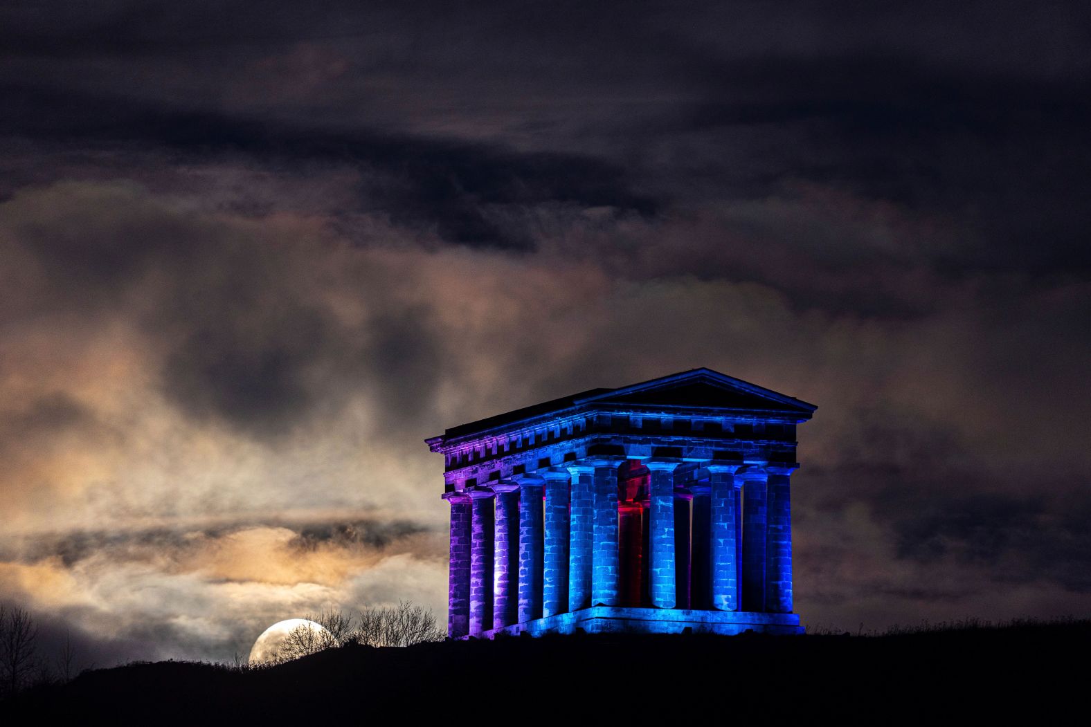 The moon, which can appear full to the naked eye about a day before and after its peak, sets on Friday behind Penshaw Monument in Sunderland, United Kingdom.