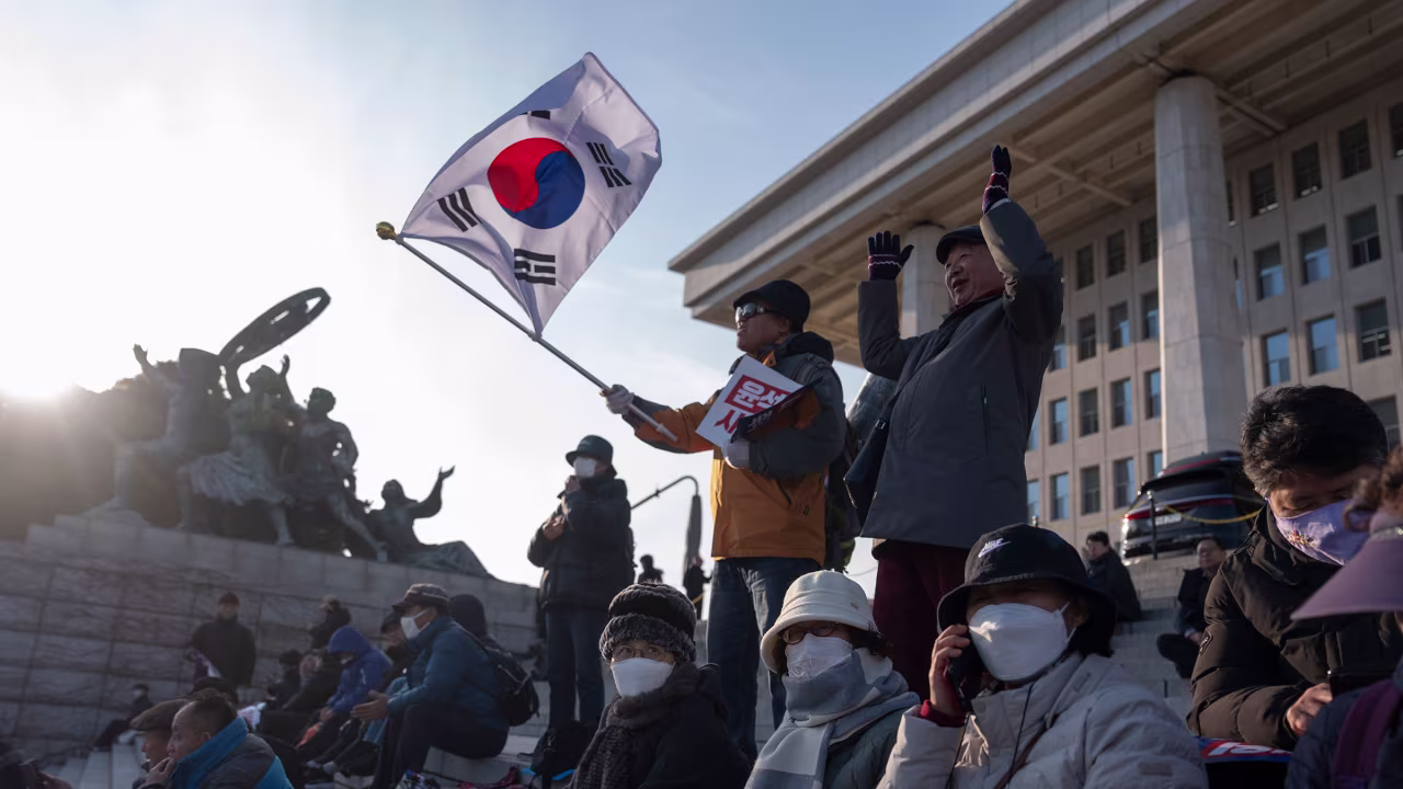 A protester waves a South Korean flag as he joins others gathering outside the National Assembly.