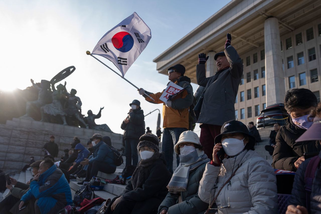 A protester waves a South Korean flag as he joins others gathering outside the National Assembly.