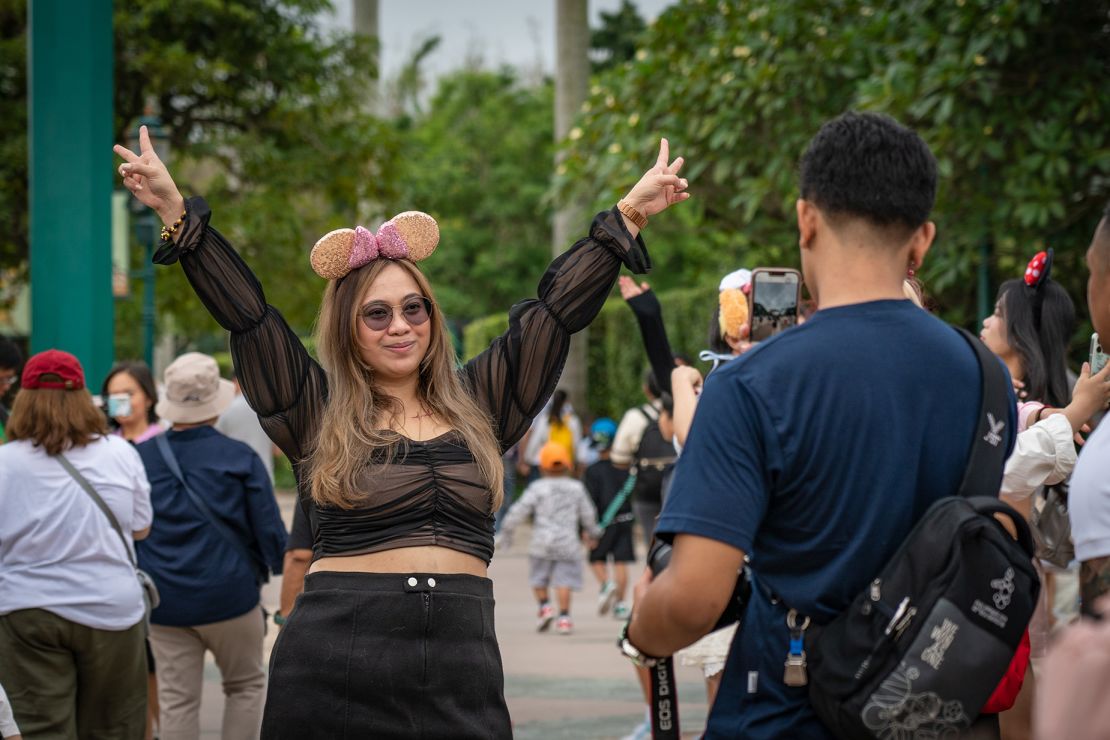 A woman poses for pictures at the entrance of Hong Kong Disneyland.