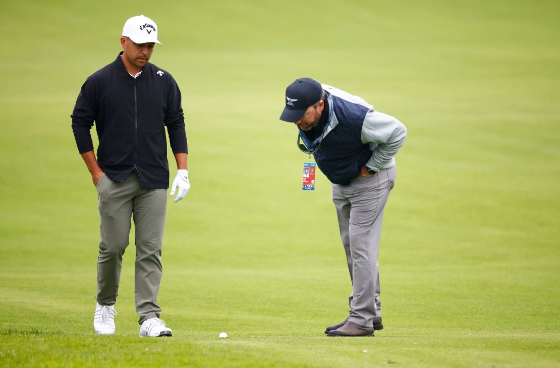 Schauffele chats with a rules official about the lie of his ball during the event.