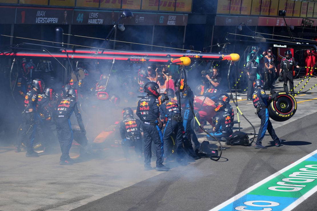 Mechanics deal with the smoke coming out of Verstappen's car in the pit lane.